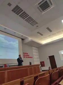 Prelegent z mikrofonem przy ekranie z prezentacją o cyberprzemocy